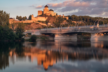 Early meddieval castle of Trencin above a modern railway bridge reflected in a river during a...
