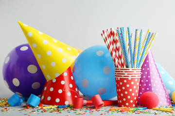 Birthday party caps, blowers and balloons on grey background