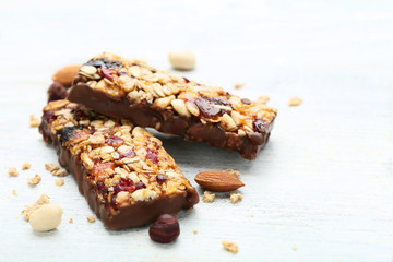 Tasty granola bars with different nuts on wooden table