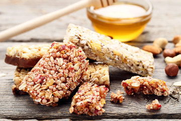 Tasty granola bars with honey in bowl on grey wooden table