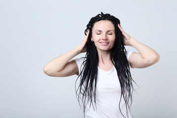 Cute young woman with dreadlocks on grey background