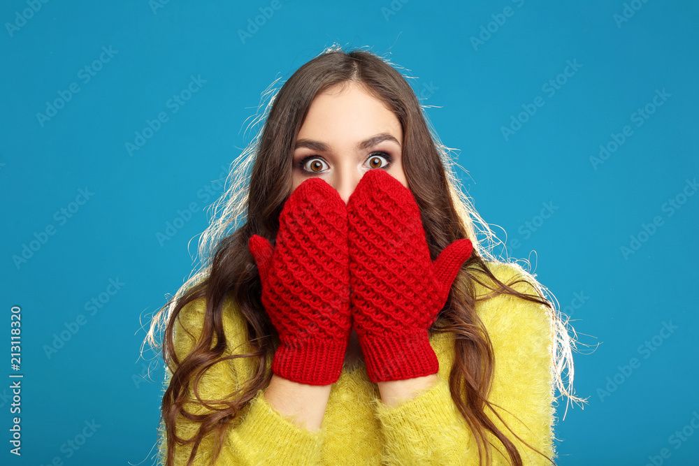 Wall mural Beautiful young girl in yellow sweater and red gloves on blue background