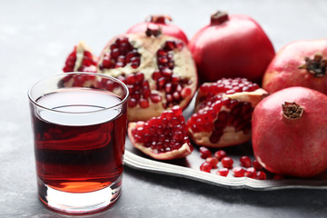 Pomegranate fruit and juice in glass on grey wooden table