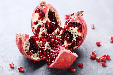 Ripe and juicy pomegranate on grey wooden table