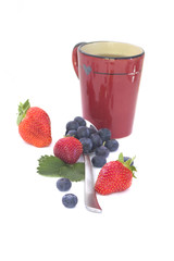 Fruit tea : strawberries and blueberries with a red mug isolated on white