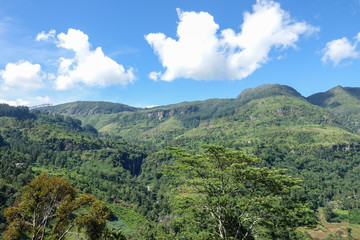 Fototapeta na wymiar Mountain landscape in a green valley. View of Puna Waterfall in Central Province, Sri Lanka