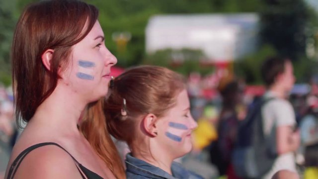 Side view of girls who watch football match supporting Argentina in fan zone