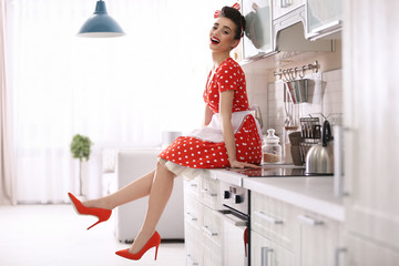 Funny young housewife sitting on kitchen counter
