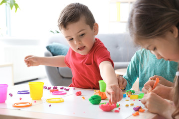 Fototapeta premium Cute little children using play dough at table indoors
