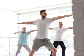 Obraz premium Group of people in sportswear practicing yoga indoors