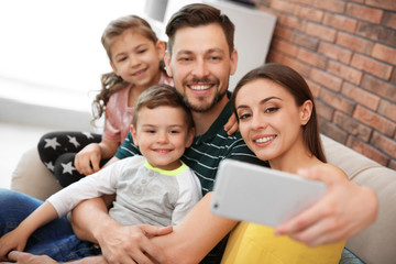 Young woman taking selfie with her family at home