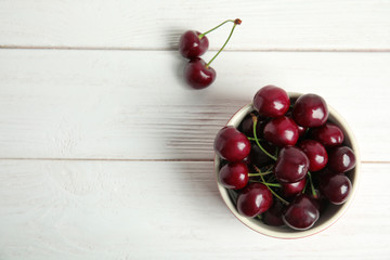 Bowl with sweet red cherries on wooden table, top view