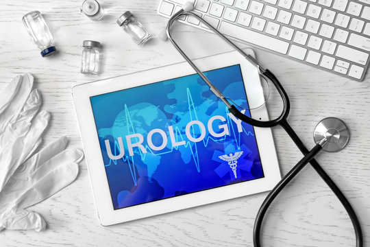 Tablet with word "UROLOGY" and medical items on table, top view
