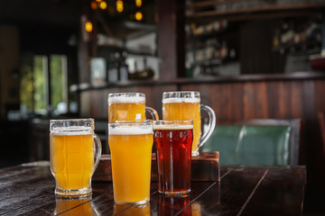 Glasses of tasty beer on wooden table in bar