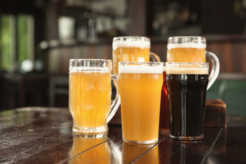 Glasses of tasty beer on wooden table in bar