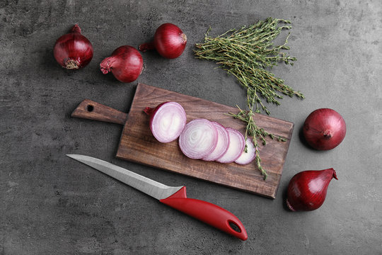 Wooden board with sliced red onion on table, top view