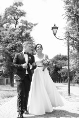 Happy newlyweds walking outdoors, black and white effect