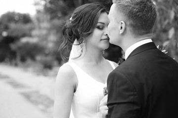 Happy newlyweds kissing outdoors, black and white effect
