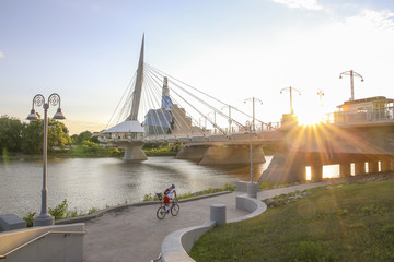 Cyclists along Red River in a sunny day. Peaceful sunset scene. Winnipeg, Canada.