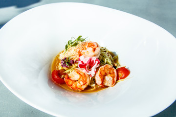 Fried shrimp with tomatoes, asparagus, green beans, decorated with flowers.