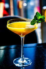 Yellow mango cocktail with mint leaf in a glass.