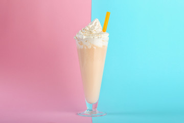 Glass with delicious milk shake on color background