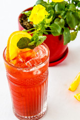 Red lemonade with a slice of lemon and orange in a glass on the table