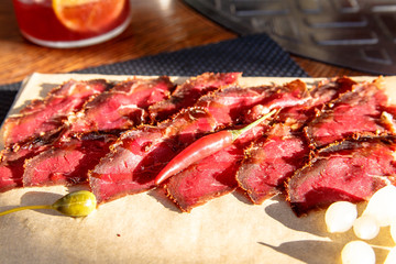 Slices beef jerky (ham, pastrami, speck, prosciutto) in the pepper are on the Board