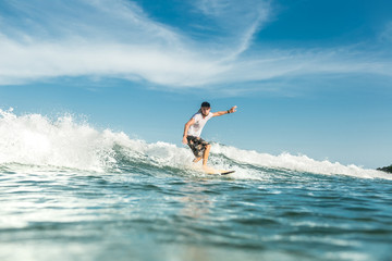 young male surfer riding waves in ocean at Nusa Dua Beach, Bali, Indonesia
