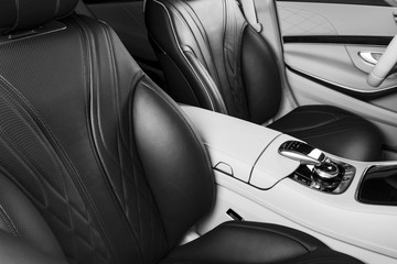 Modern Luxury car inside. Interior of prestige modern car. Comfortable leather seats. Perforated leather cockpit. Modern car interior details. Media control buttons. Black and white
