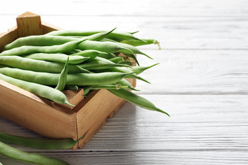 Wooden crate with fresh green beans on table