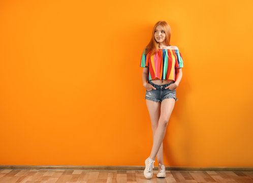 Young Woman In Stylish Jean Shorts Near Color Wall