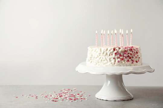 Birthday cake with candles on table against light background