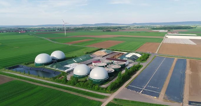 Plant for the production of biogas in the green field, plant for the production of biogas against the background of wind generators view from above