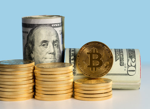 Bitcoin coins in front of bank rolls of US currency