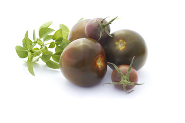 Black tomatoes and basil isolated on white
