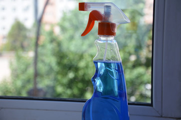 Woman cleaning a window with cleaning sprayer.