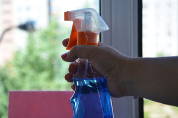 Woman cleaning a window with cleaning sprayer.