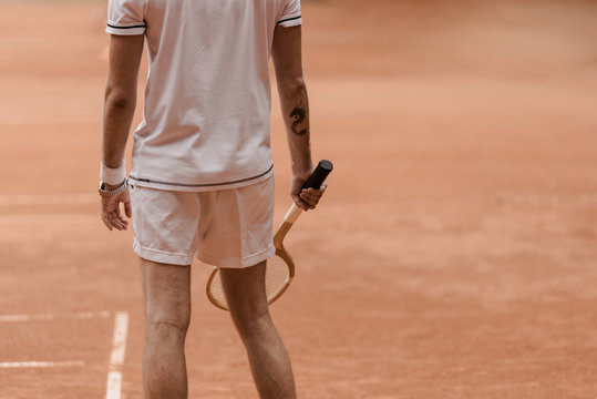 cropped image of tennis player standing with racket at tennis court