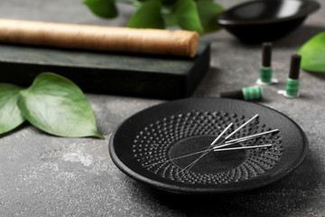 Plate with needles for acupuncture on dark table - obrazy, fototapety, plakaty