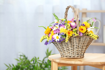 Fototapeta na wymiar Wicker basket with beautiful wild flowers on table indoors
