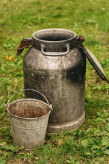 Iron can and old rusty bucket on green grass background, rustic concept