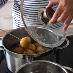 Home cook checks on potatoes boiling in a pan