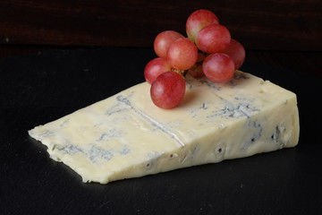 Gorgonzola cheese and grapes on dark background.