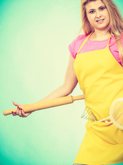 Woman wearing apron holding rolling pin