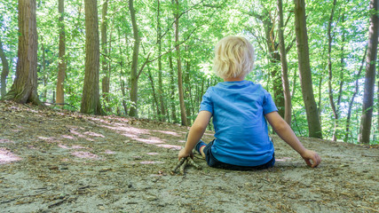 Naklejka na ściany i meble Kind sitzt im Wald auf einem Weg