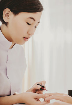 Pretty Asian Manicurist Applying Nail Polish