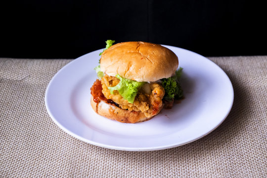 Chicken Hamburger on the white plate with black background. Selective Focus.Visible Noise,Image Blur When View at Full Resolution.