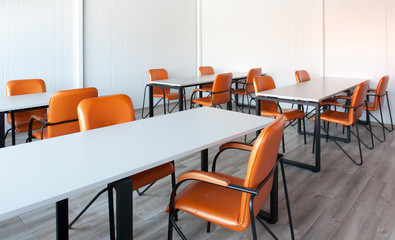 Dining room at factory. Orange chairs. White tables.