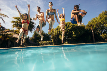 Friends jumping into a swimming pool and having fun - Powered by Adobe